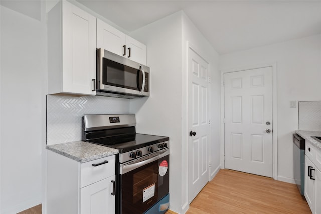 kitchen featuring light stone countertops, white cabinetry, appliances with stainless steel finishes, and light hardwood / wood-style flooring