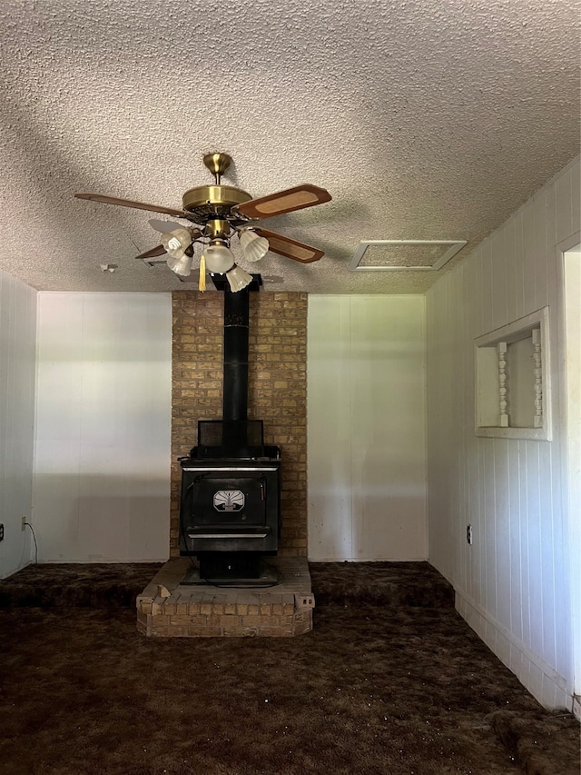 interior details featuring a textured ceiling, a wood stove, and carpet floors