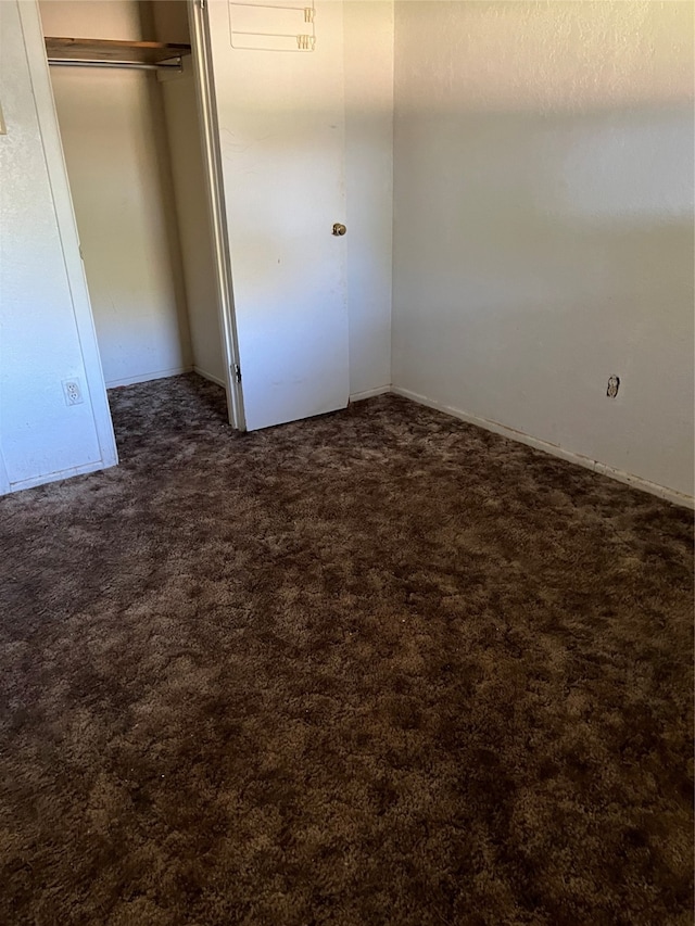 unfurnished bedroom with dark carpet and a closet