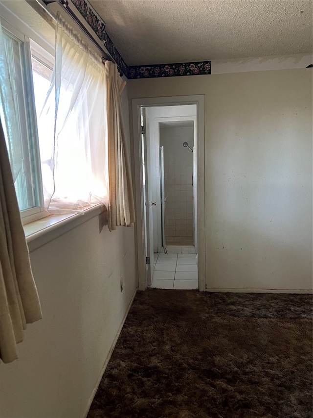 hall with a textured ceiling and light colored carpet