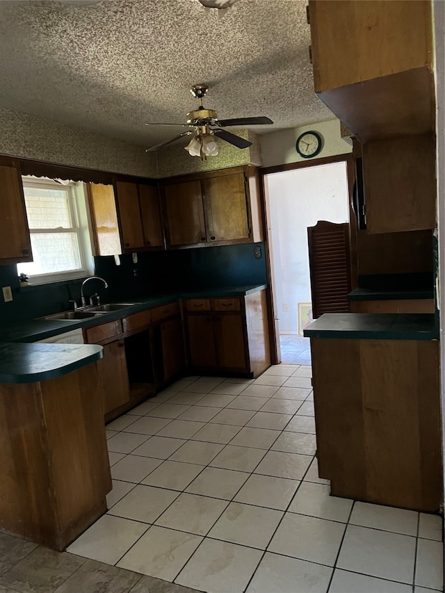 kitchen featuring a textured ceiling, sink, kitchen peninsula, light tile patterned floors, and ceiling fan