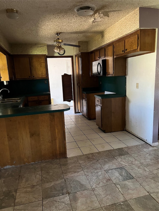 kitchen with a textured ceiling, kitchen peninsula, sink, and ceiling fan