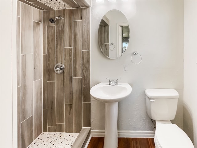 bathroom featuring wood-type flooring, tiled shower, and toilet