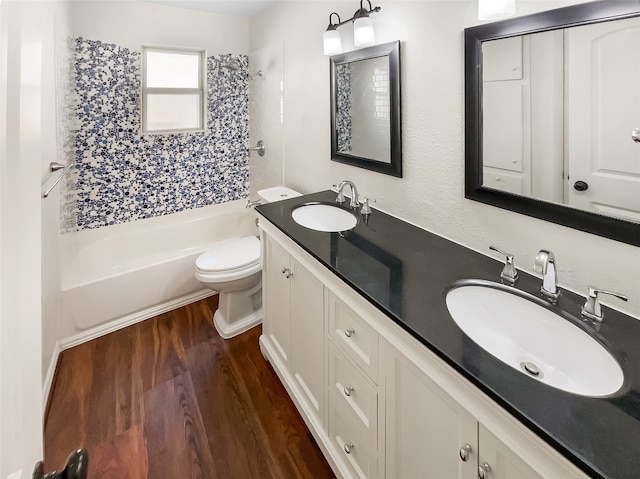 full bathroom with hardwood / wood-style floors, tiled shower / bath, vanity, and toilet