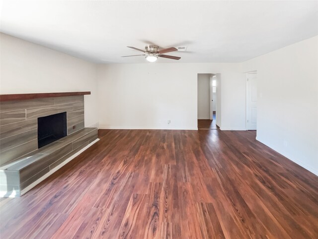 unfurnished living room with a tiled fireplace, ceiling fan, and dark hardwood / wood-style flooring