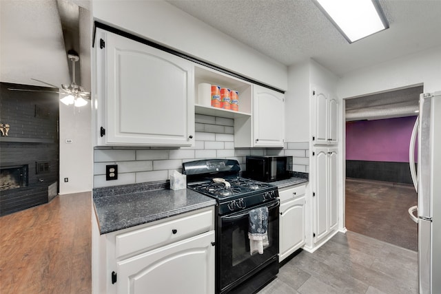 kitchen with black appliances, a fireplace, white cabinetry, and ceiling fan