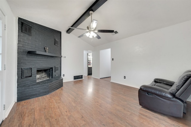 living room featuring vaulted ceiling with beams, a fireplace, ceiling fan, and hardwood / wood-style flooring