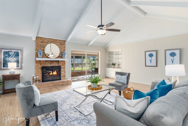 living room featuring a brick fireplace, lofted ceiling with beams, light hardwood / wood-style floors, and ceiling fan