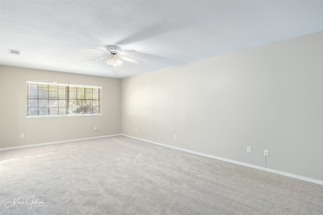 empty room featuring ceiling fan, light colored carpet, and a textured ceiling