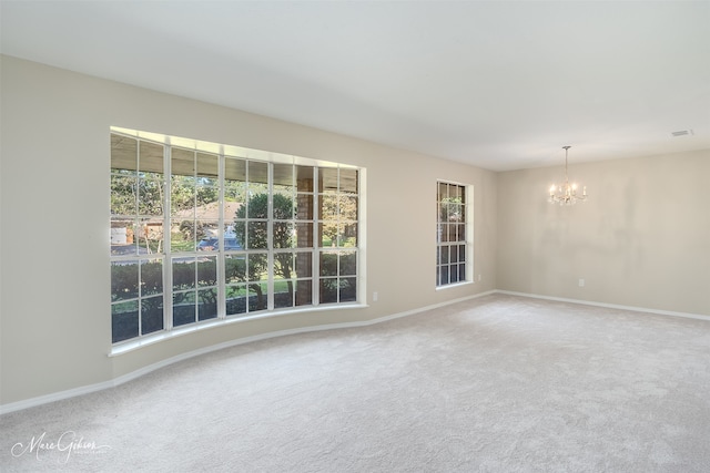 carpeted spare room with an inviting chandelier