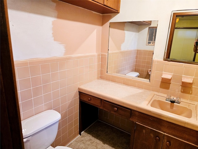 bathroom featuring vanity, toilet, and tile walls