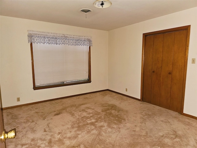 unfurnished bedroom featuring a closet and light colored carpet