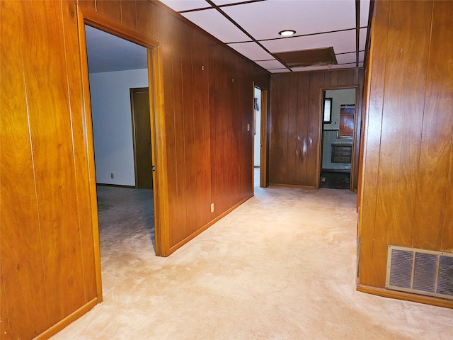 hallway with wood walls and light colored carpet