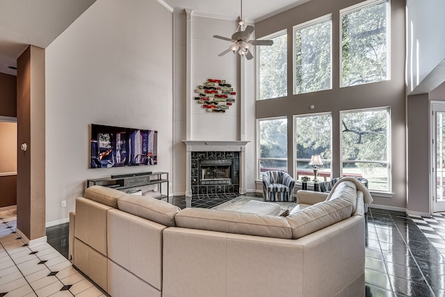 tiled living room with a towering ceiling, a high end fireplace, ornamental molding, and ceiling fan