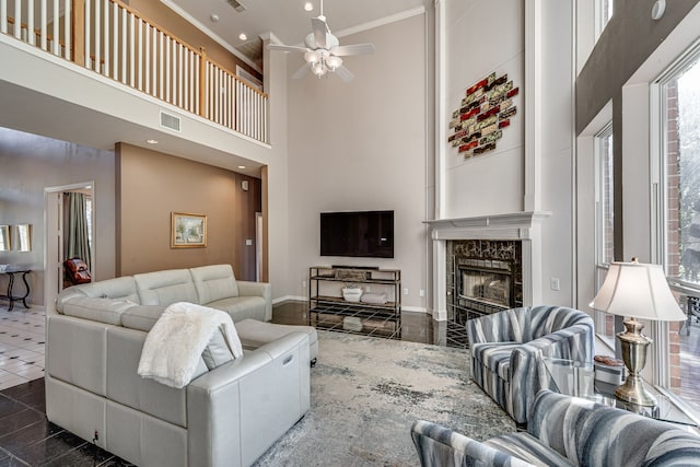 living room with a high ceiling, a premium fireplace, dark tile patterned flooring, and ceiling fan