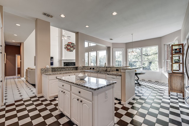 kitchen with white cabinetry, a center island, white dishwasher, kitchen peninsula, and pendant lighting