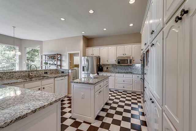 kitchen with white cabinetry, sink, stainless steel appliances, and a center island