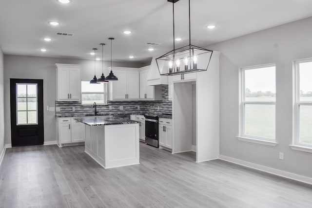 kitchen with a kitchen island, stainless steel range oven, plenty of natural light, decorative light fixtures, and white cabinets