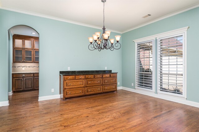 dining room featuring hardwood / wood-style flooring, ornamental molding, and a notable chandelier