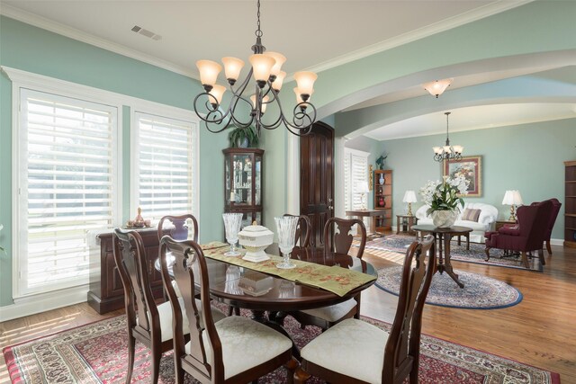 dining area featuring wood-type flooring, a notable chandelier, and ornamental molding