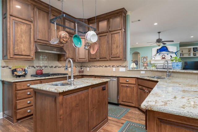 kitchen with an island with sink, light stone counters, stainless steel appliances, and light hardwood / wood-style floors