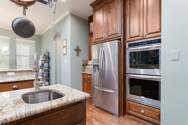 kitchen with light stone countertops, sink, crown molding, and stainless steel appliances