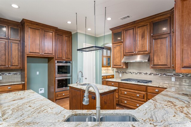 kitchen featuring light stone counters, decorative light fixtures, appliances with stainless steel finishes, and kitchen peninsula