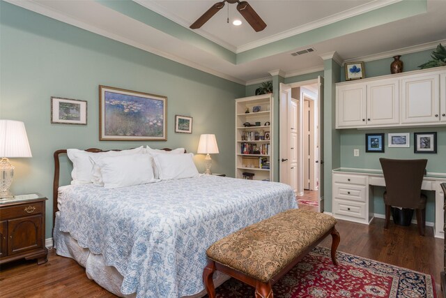 bedroom with ceiling fan, dark wood-type flooring, a raised ceiling, and built in desk