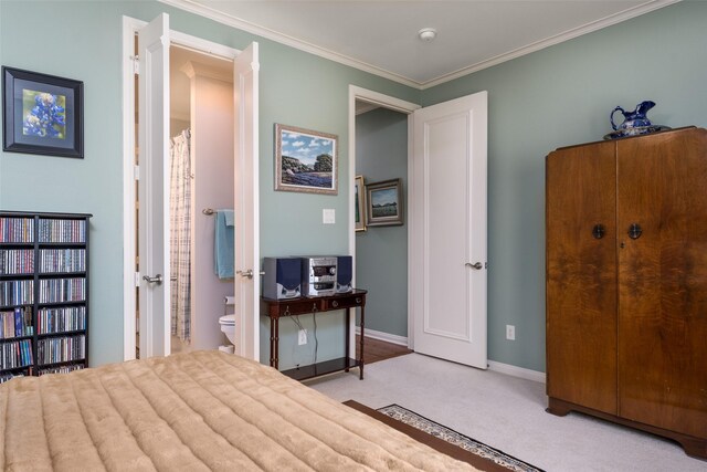 carpeted bedroom with ornamental molding and ensuite bath