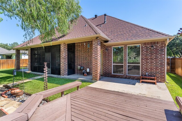 back of house with a wooden deck, a sunroom, a yard, and a patio