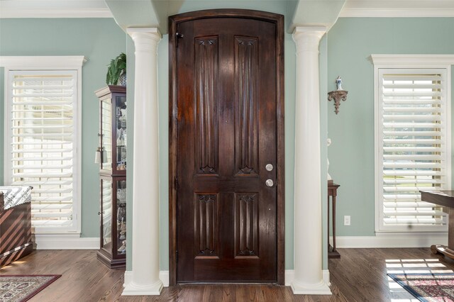 entryway with dark hardwood / wood-style flooring, crown molding, and ornate columns