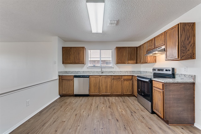 kitchen with appliances with stainless steel finishes, a textured ceiling, light wood-type flooring, and sink