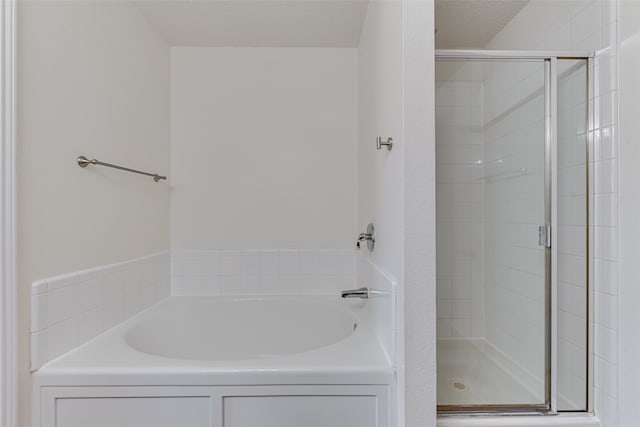 bathroom featuring a textured ceiling and independent shower and bath