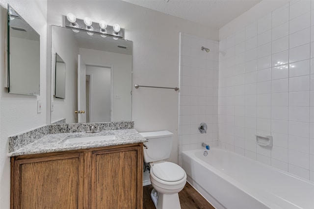 full bathroom with hardwood / wood-style flooring, tiled shower / bath combo, vanity, and toilet