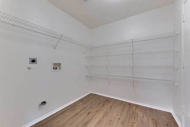 washroom featuring a textured ceiling, hardwood / wood-style flooring, electric dryer hookup, hookup for a gas dryer, and hookup for a washing machine