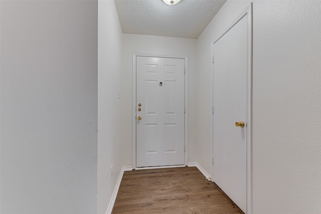 doorway with a textured ceiling and light hardwood / wood-style floors