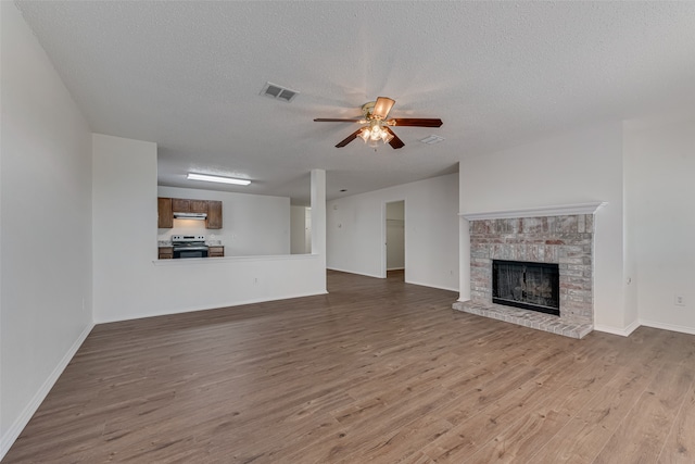 unfurnished living room with ceiling fan, a textured ceiling, light hardwood / wood-style flooring, and a fireplace