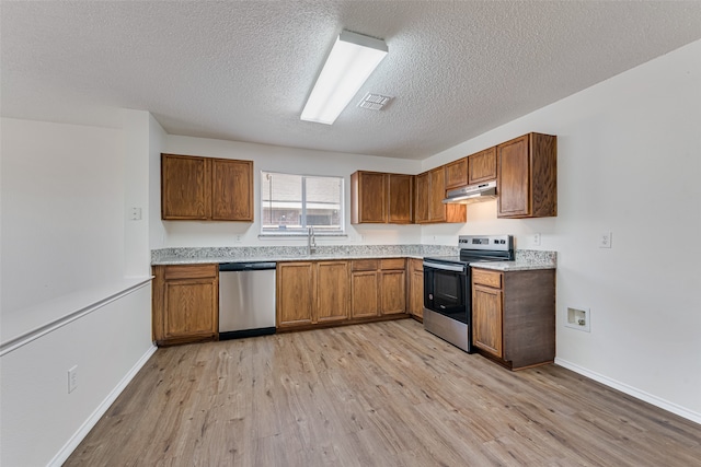 kitchen featuring light wood-type flooring, a textured ceiling, appliances with stainless steel finishes, and sink