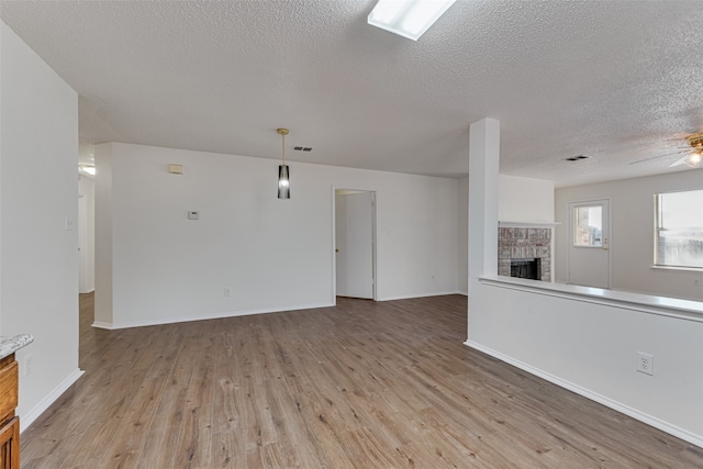 unfurnished living room featuring ceiling fan, a textured ceiling, and light hardwood / wood-style floors