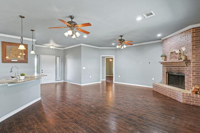 unfurnished living room featuring dark hardwood / wood-style flooring, a brick fireplace, a textured ceiling, ceiling fan, and crown molding