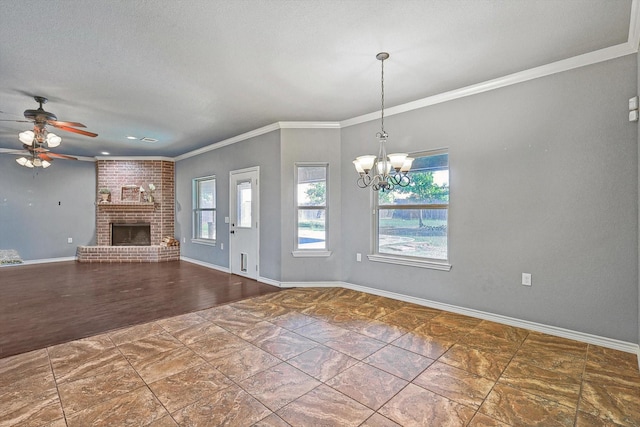 unfurnished living room with ornamental molding, a brick fireplace, ceiling fan with notable chandelier, and a textured ceiling