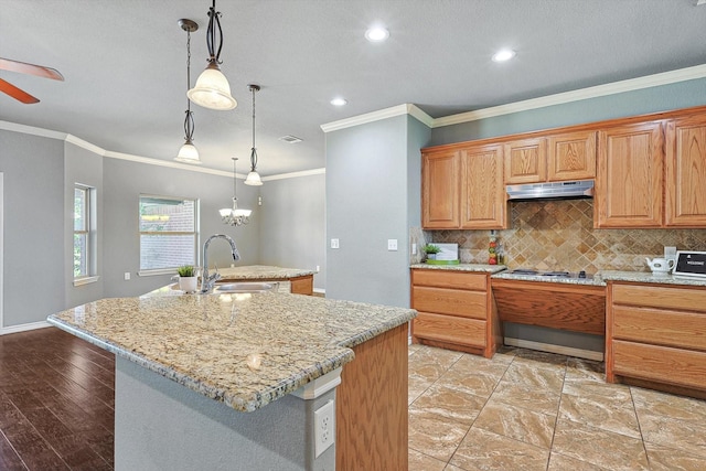 kitchen with decorative backsplash, sink, an island with sink, and hanging light fixtures