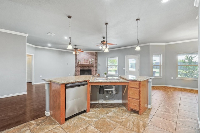 kitchen featuring decorative light fixtures, a fireplace, an island with sink, and dishwasher