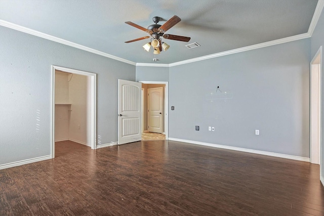 unfurnished bedroom featuring dark wood-type flooring, ceiling fan, crown molding, and a spacious closet