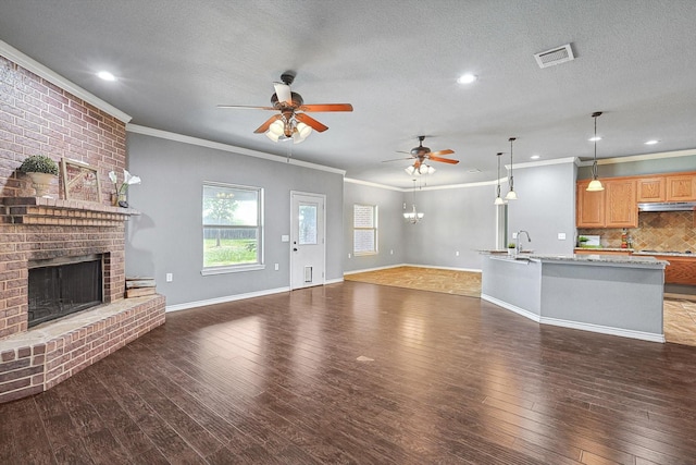 unfurnished living room with sink, dark wood-type flooring, ceiling fan, a fireplace, and a textured ceiling