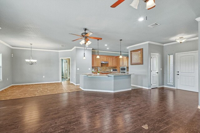 kitchen with ceiling fan, crown molding, an island with sink, and hanging light fixtures