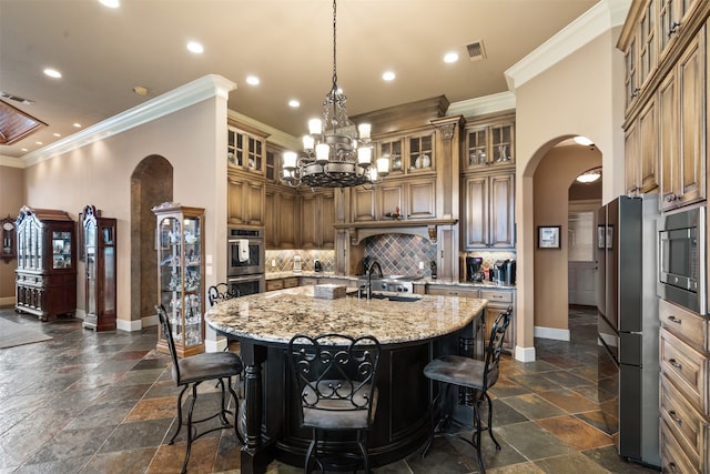 kitchen with a breakfast bar area, an island with sink, stainless steel appliances, crown molding, and light stone countertops