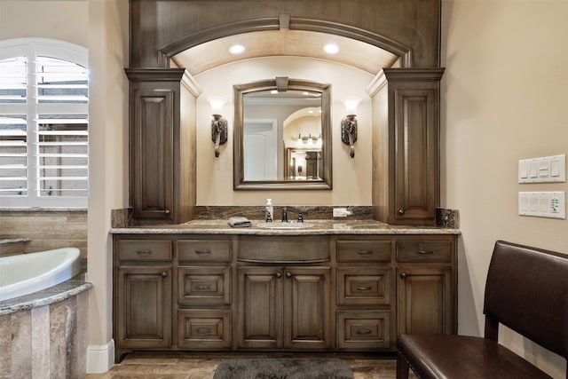 bathroom with ornamental molding, vanity, and a washtub