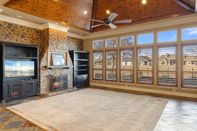 unfurnished living room with stone tile floors, wood ceiling, ornamental molding, a tray ceiling, and a stone fireplace