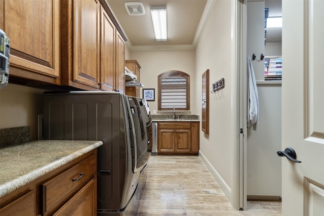 laundry room with crown molding, light hardwood / wood-style floors, independent washer and dryer, and cabinets